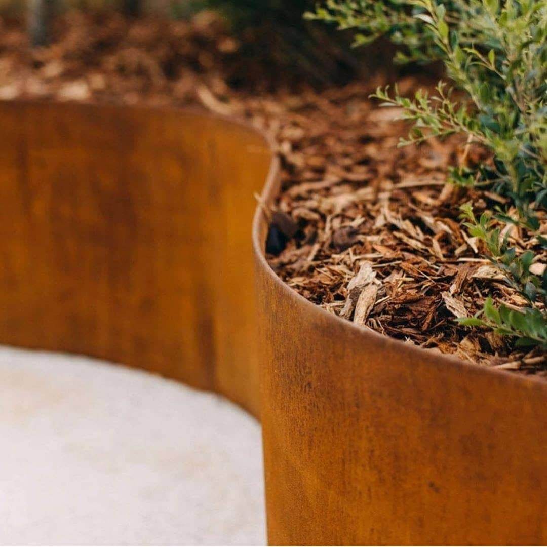 garden edging with a rust finish used for retaining a garden bed of mulch and native plants